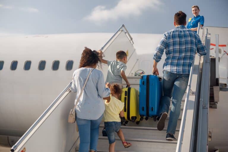 A family with luggage on the steps of an airplane